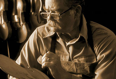 older violin maker workinig on instrument